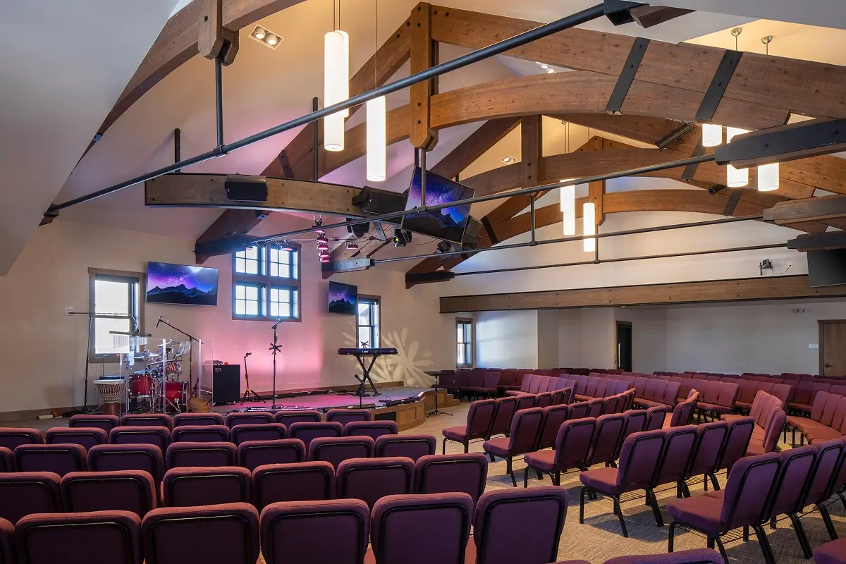 Angled view of a remodeled sanctuary featuring wood and steel trusses with updated lighting.
