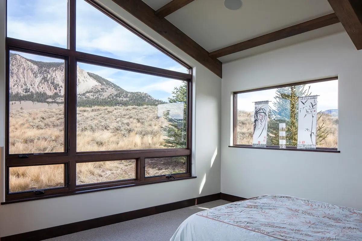 Bedroom window framing scenic Colorado mountain views with natural wood trim and minimalist decor.
