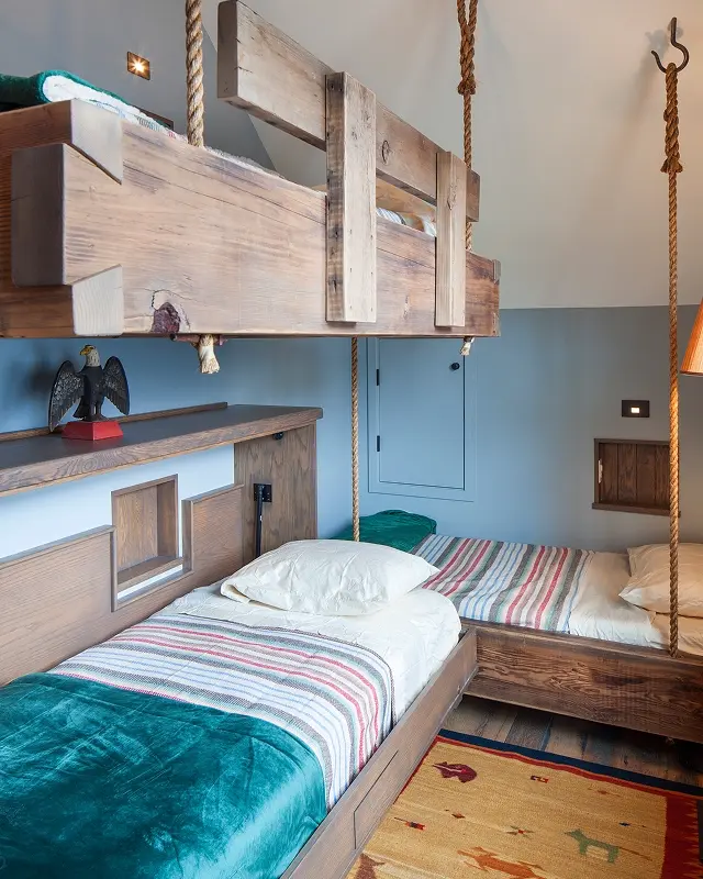 Bunk room with rustic hanging beds, natural wood finishes, and cozy mountain styling.