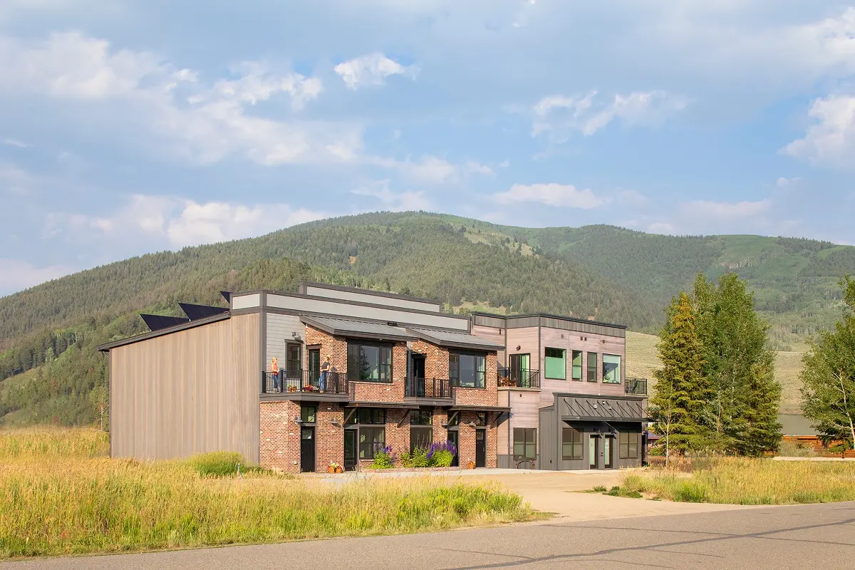 Modern mixed-use building in Crested Butte South featuring brick and wood siding against a scenic mountain backdrop.