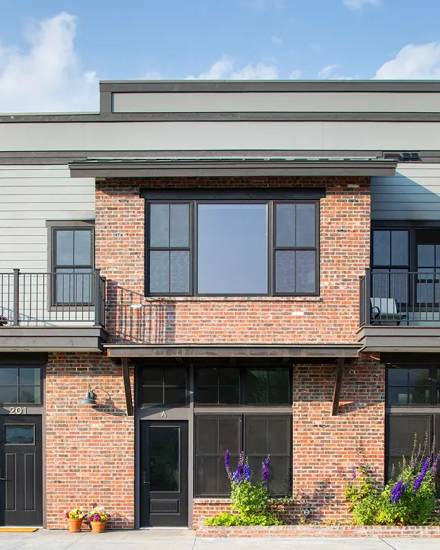Detailed view of brick-and-siding façade with black trim and potted plants at the Pioneer Building in Crested Butte.