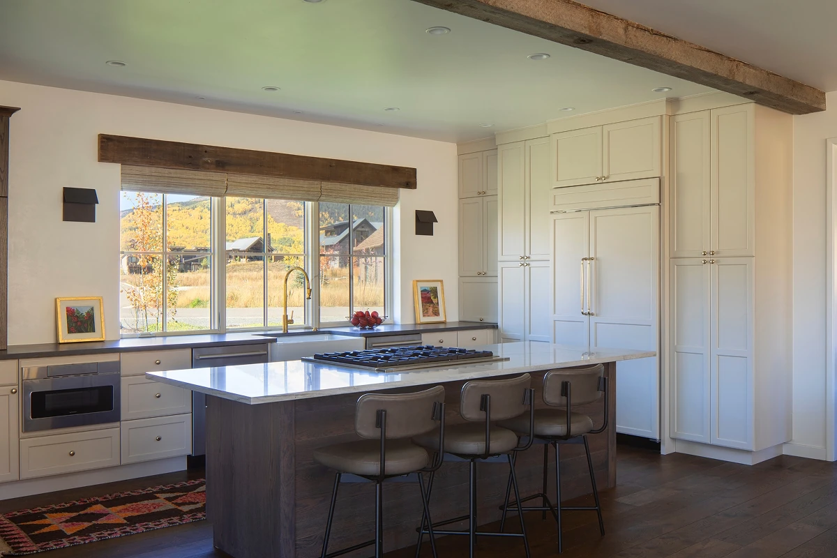 Spacious Colorado kitchen with a dark island, marble countertops, and mountain views through oversized windows.