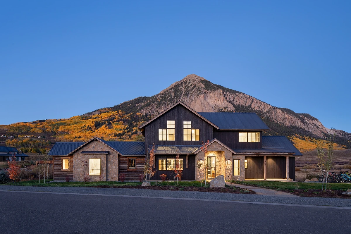 Front elevation of a modern mountain home at dusk, blending stone, wood, and clean lines.