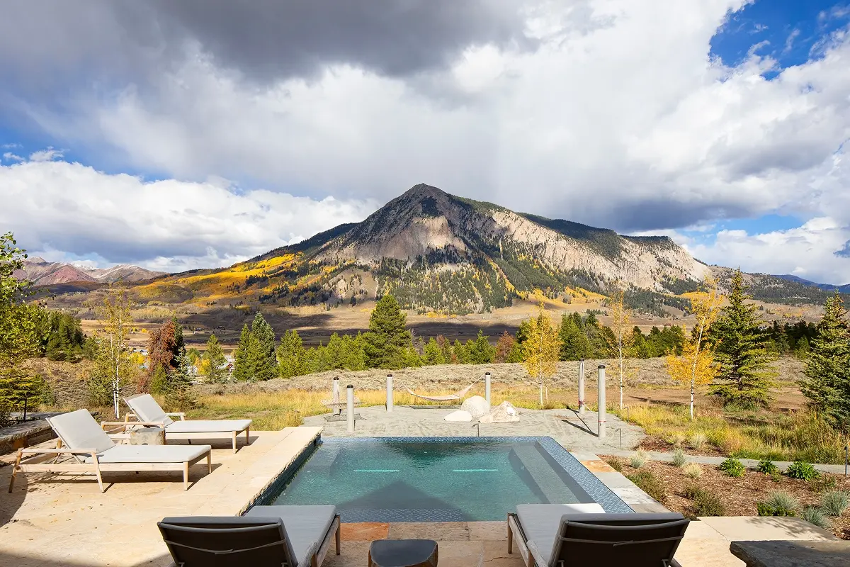 Hot tub and pool retreat framed by golden aspens and the iconic silhouette of Mount Crested Butte.