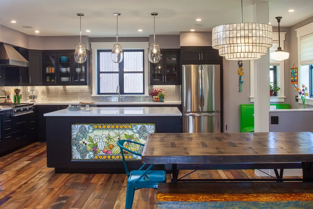 Custom Crested Butte kitchen with black cabinetry, pendant lights, and a backlit stained-glass panel integrated into the island.