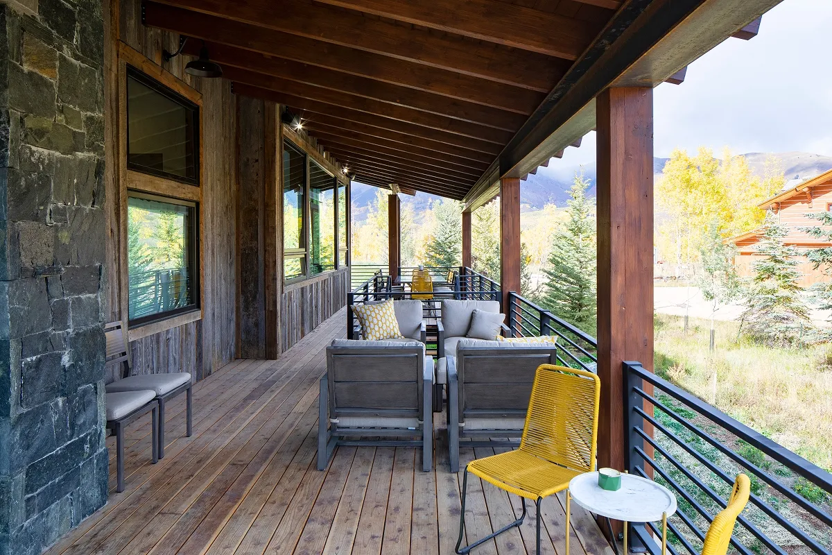Covered patio lounge at Surround House with wood deck, mountain views, and cozy seating.