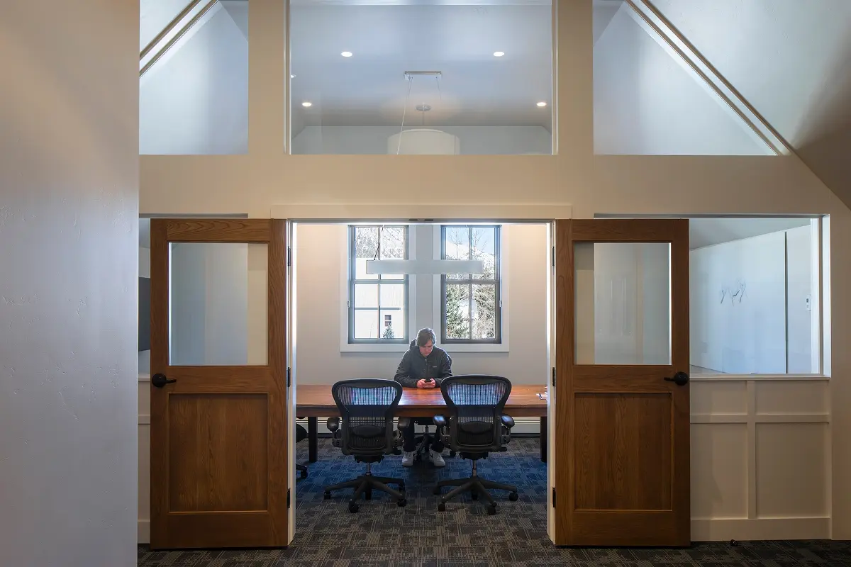 Glass-front conference room with natural light and wood accents inside a renovated building.