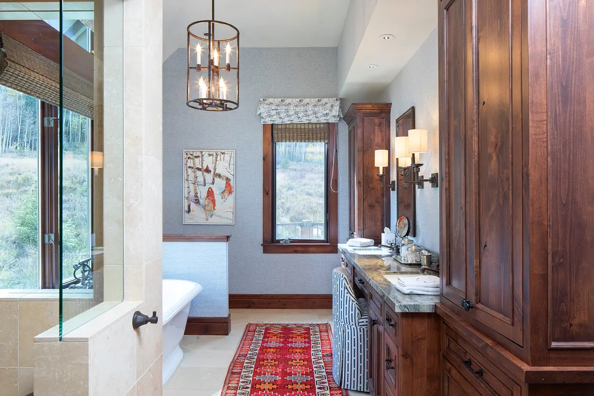Rustic luxury bathroom featuring warm wood cabinetry, soaking tub, and mountain-facing windows.