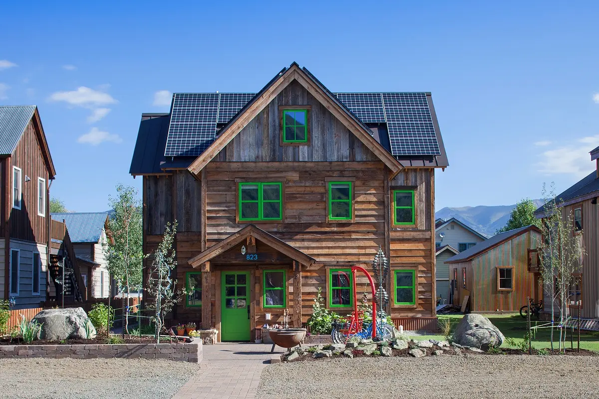 Custom mountain home in Crested Butte with reclaimed siding, bright green windows, and rooftop solar panels along a gable roofline.