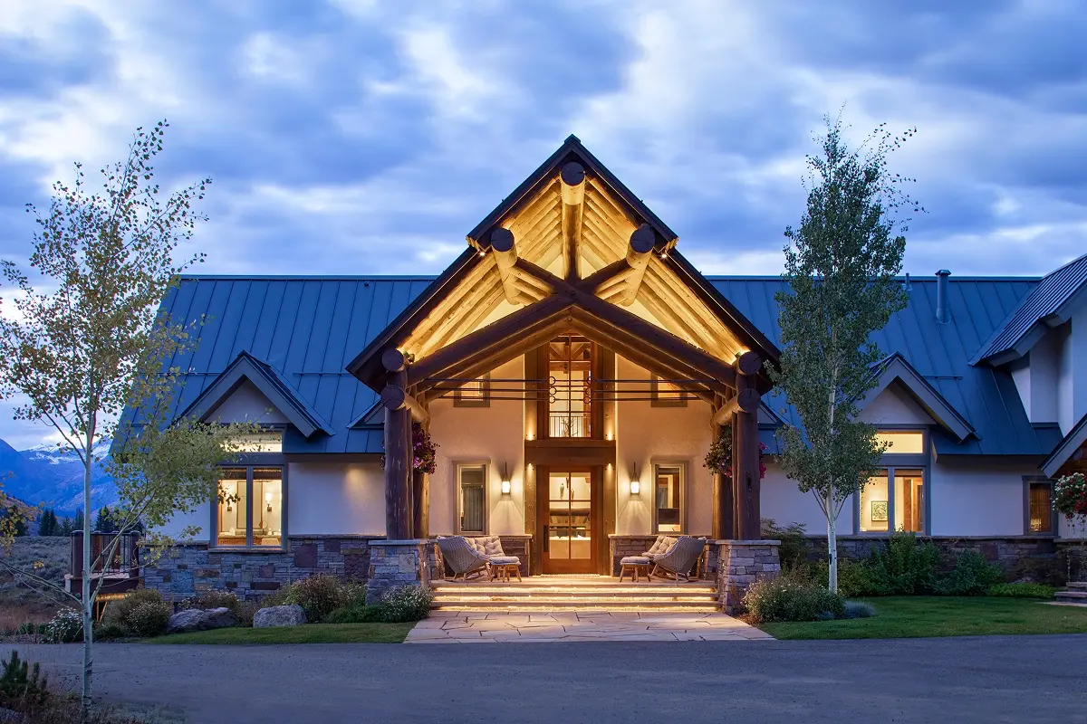 Front porch of a luxury mountain retreat with exposed log beams and warm architectural lighting.