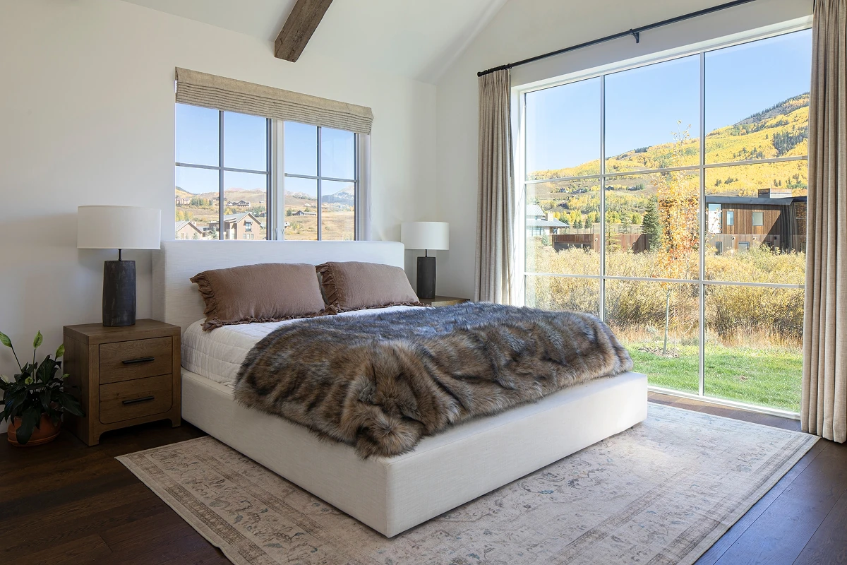 Modern mountain bedroom with vaulted ceilings and expansive windows overlooking fall colors in Crested Butte.