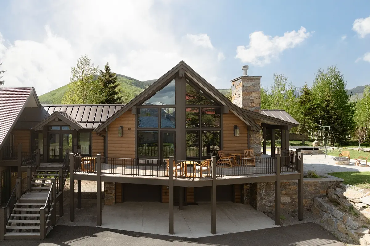 Exterior view of modern mountain home in Mount Crested Butte with log siding, gable roof, and elevated deck.