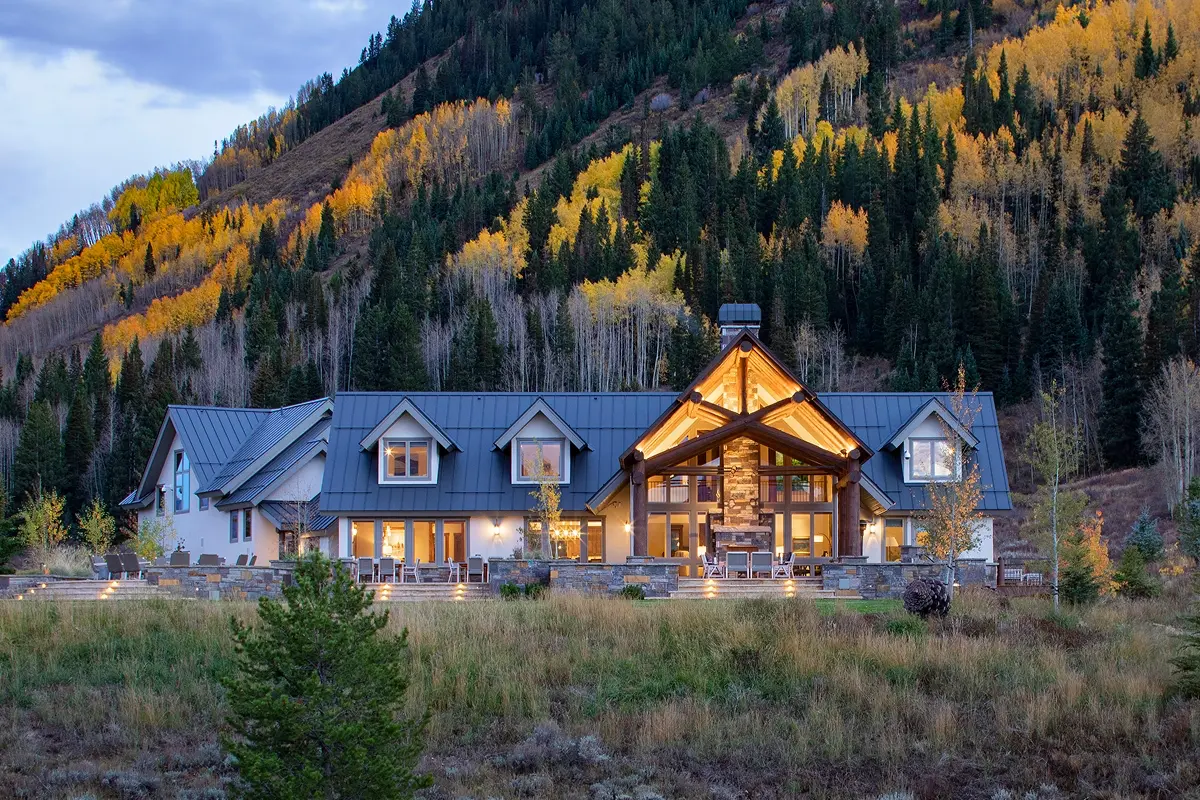 Full exterior of Crested Butte mountain home against golden aspens and a dusky sky.