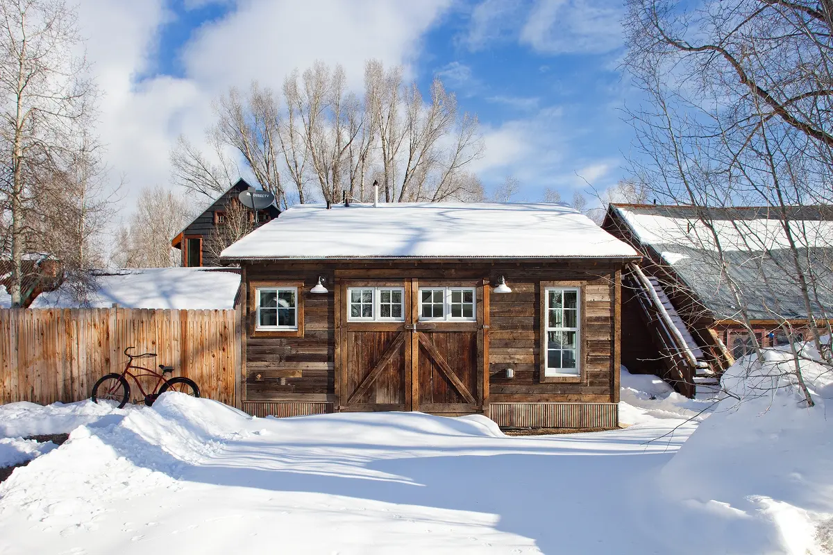 Crested Butte rental cabin with original barn doors, surrounded by snow and winter trees.