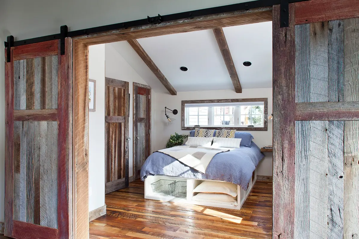 Rustic barn door entry to bedroom with reclaimed wood beams and cozy linens.