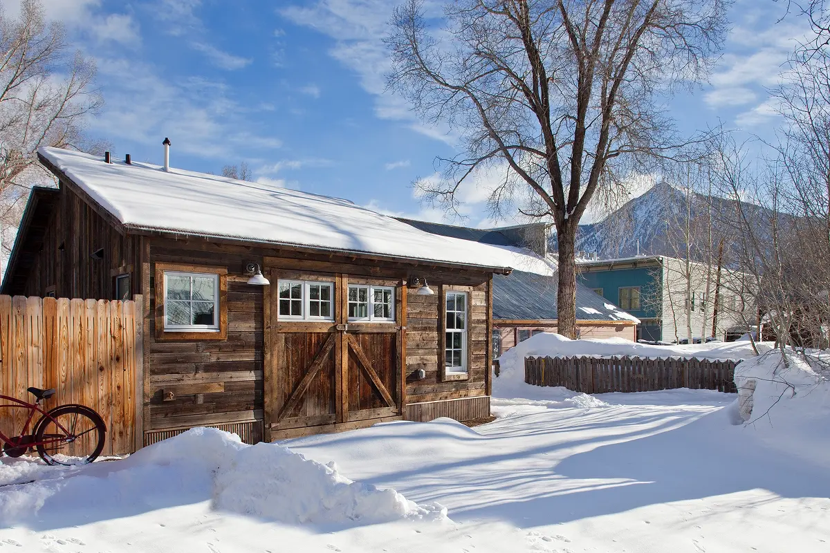 Historic Crested Butte winter cabin with mountain backdrop and preserved wood siding.