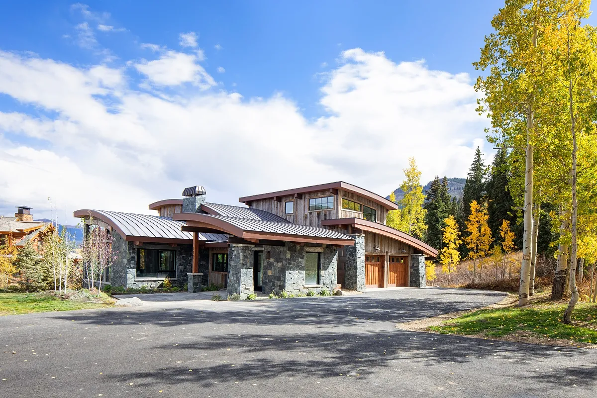 Front elevation of Surround House showcasing curved rooflines and natural materials.