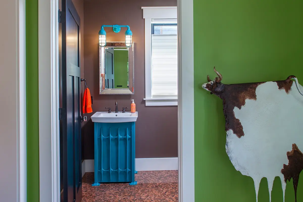 Bold bathroom design with bright green walls, brown tile, and a blue custom vanity blending rustic and modern mountain materials.