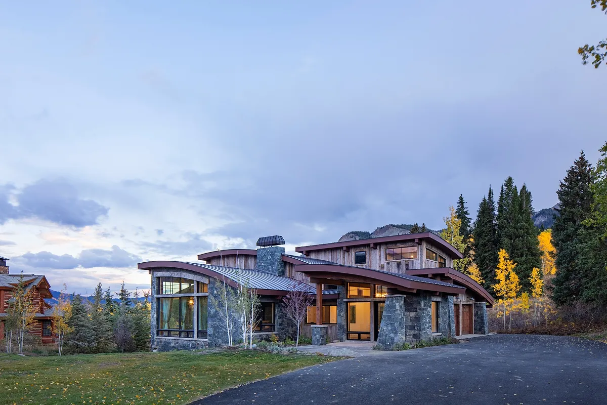 Evening view of Surround House entry framed by trees and warm interior lighting.