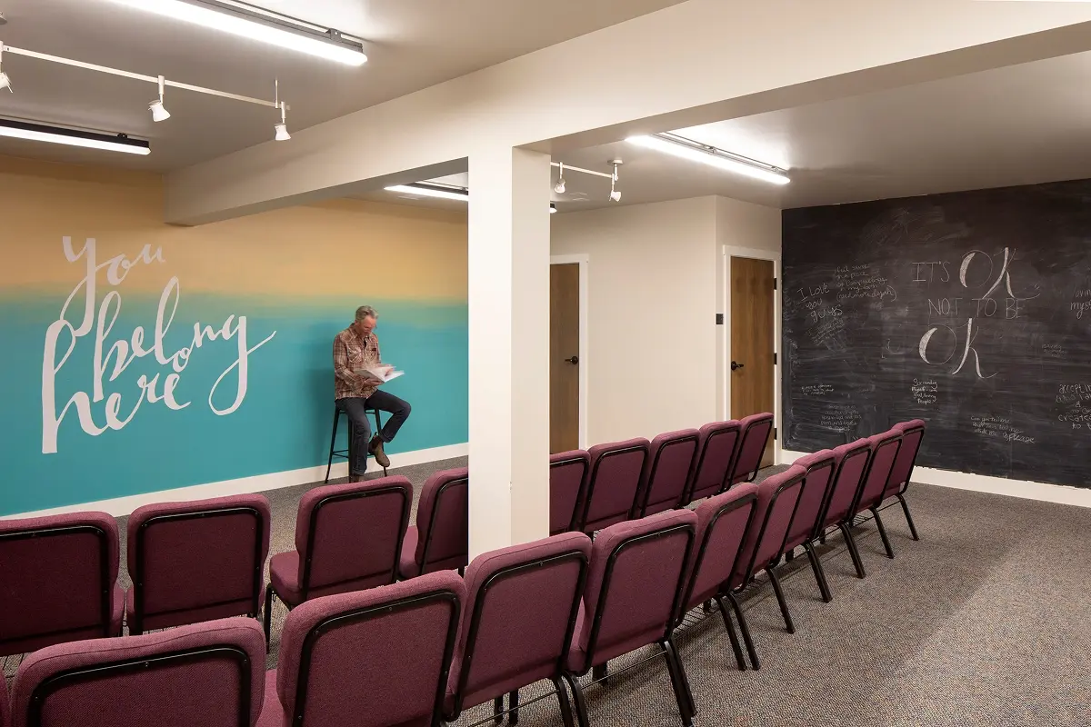 Lower-level classroom with mural walls, theater seating, and warm, welcoming light.