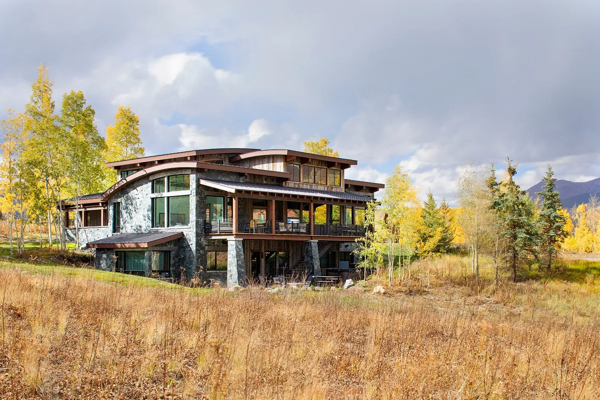 Full rear view of Surround House with extensive glazing, multi-level decks, and surrounding fall landscape.