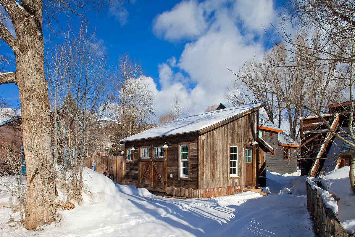 Snow-covered historic cabin renovation in downtown Crested Butte with vintage charm.