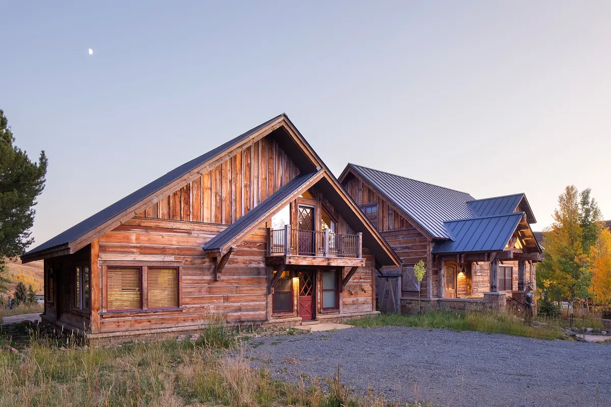 Exterior of log cabin mountain retreat at twilight with glowing windows and natural siding.