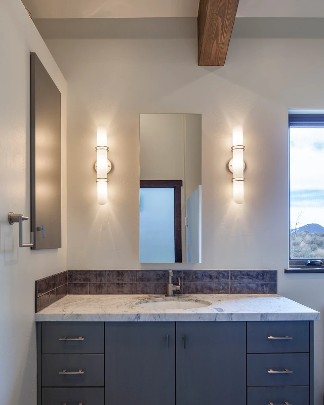 Minimalist bathroom with marble vanity, sconces, and dark wood cabinetry in a Crested Butte mountain home.