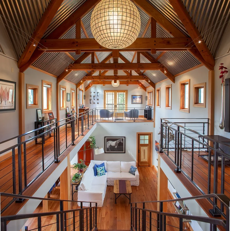 Renovated loft with exposed wood trusses and open mezzanine overlooking the bright central living area.