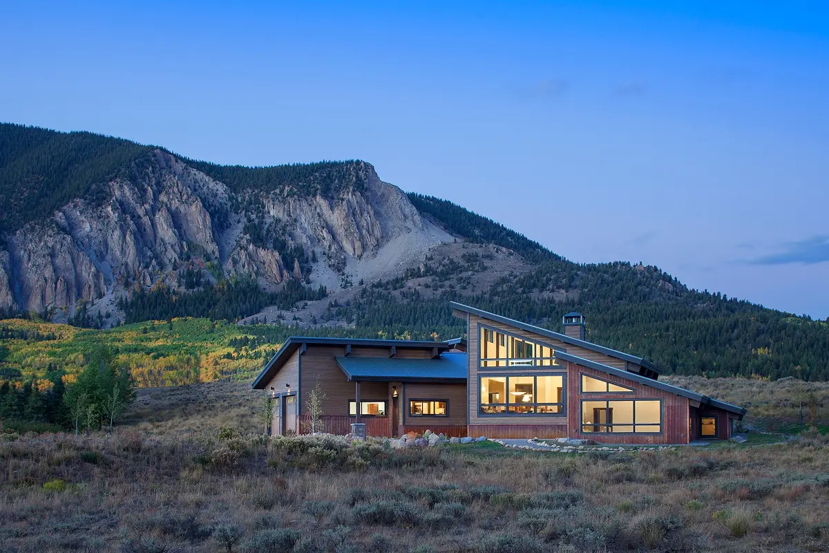 Modern mountain home in Crested Butte with slanted rooflines and large windows nestled in an open high alpine landscape.