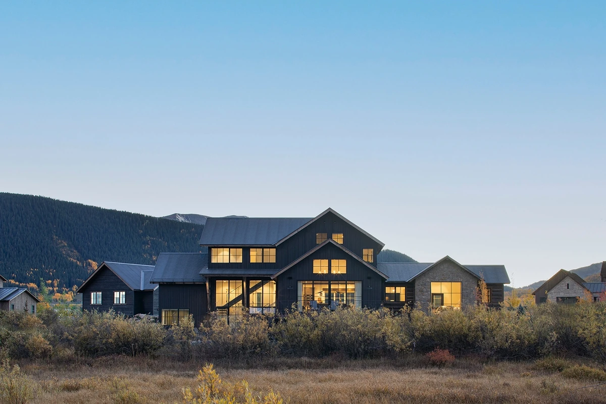 Contemporary home with sunset light pouring across meadow views and surrounding modern architecture.