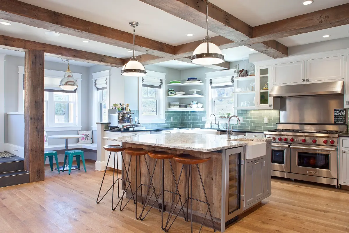 Chef’s kitchen with reclaimed beams, island seating, stainless steel Wolf range, and subway tile.