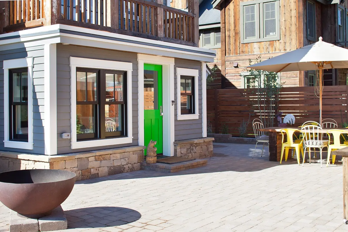 Backyard patio with fire bowl, outdoor dining area, and bright green door entrance.