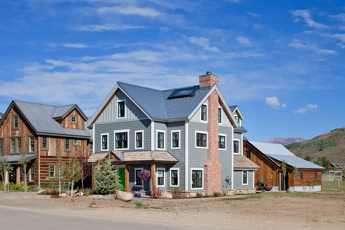 Street view of home with brick chimney, board and batten siding, and natural wood accents.