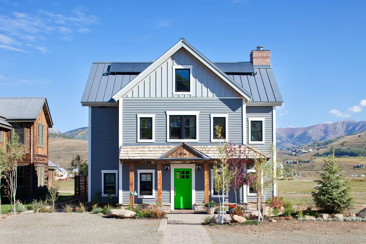 Grey Victorian-inspired home with green front door and mountain views in Crested Butte, Colorado.