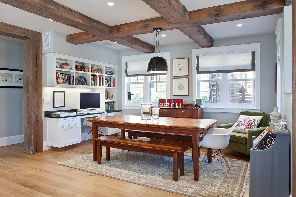 Home office with built-in shelves, desk area, exposed beams, and large wood dining table.