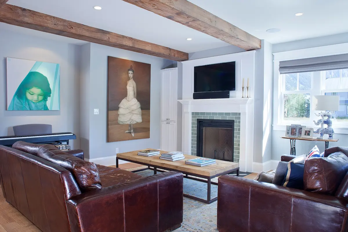 Cozy living room with leather seating, fireplace, and exposed wood ceiling beams.