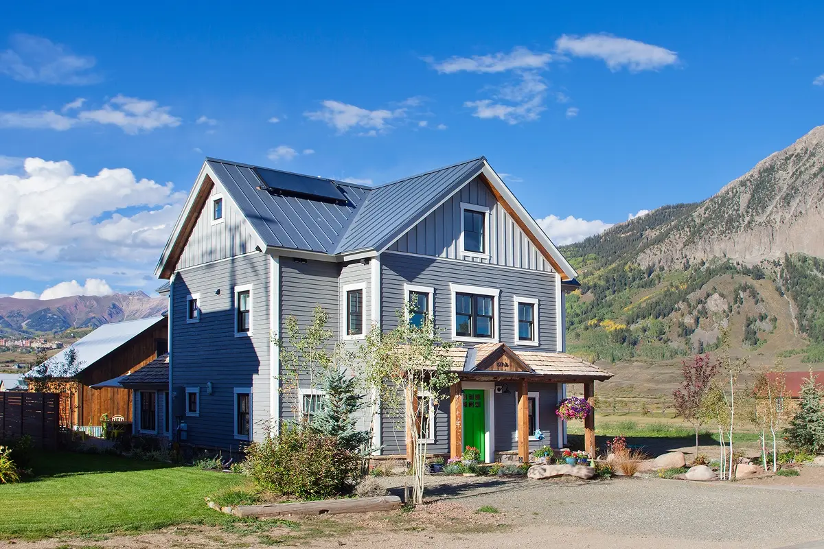 Side view of home with detached structure and mountain views beyond Elk Avenue.