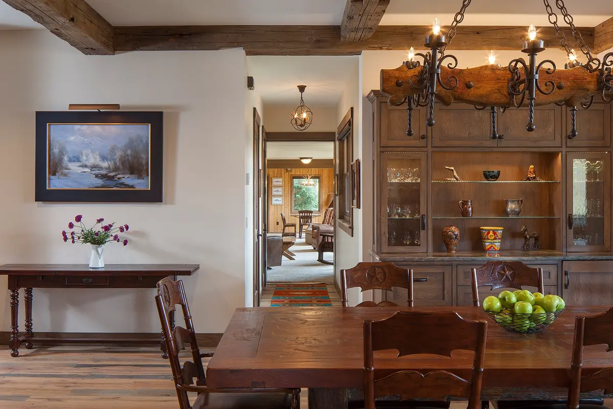 Rustic mountain dining room with wood furniture and antler chandelier under timber ceiling