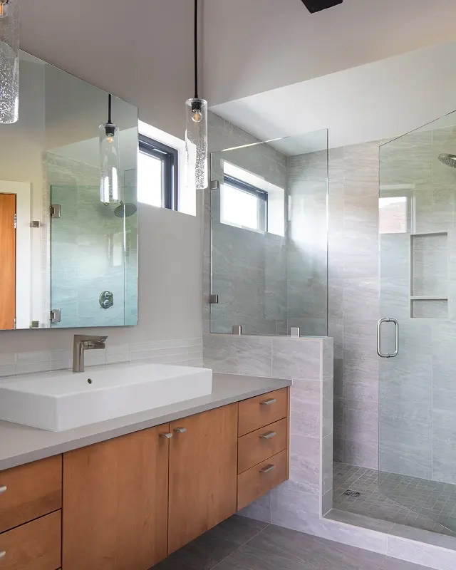 Luxury mountain home bathroom with floating vanity, glass shower, and textured tile details.