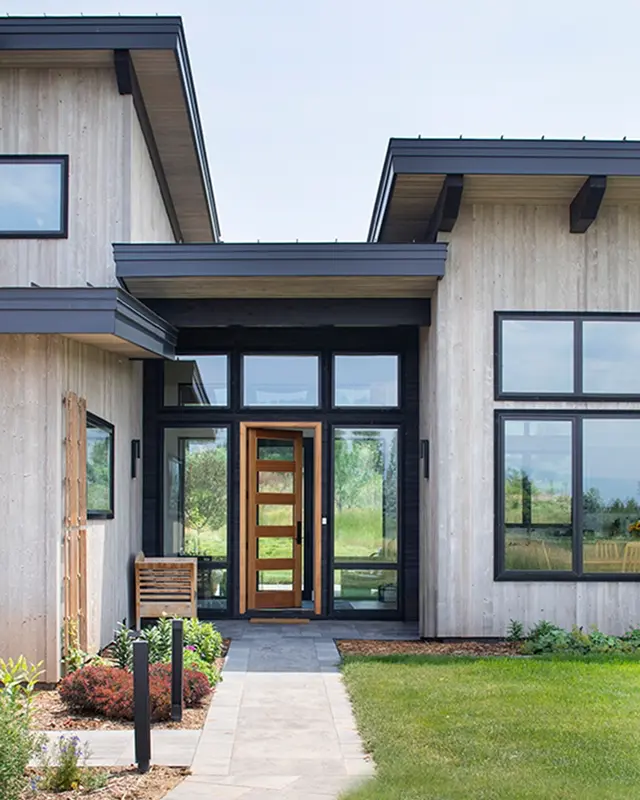 Modern mountain home entry with glass front door and vertical wood siding in Colorado.