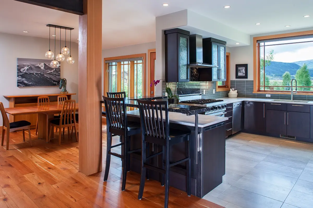 Renovated open kitchen with black cabinetry, tile flooring, and seamless flow into light-filled dining area.