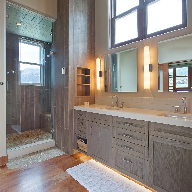 Contemporary primary bathroom with dual vanities, underlighting, tall mirrors, and glass shower with tiled walls.