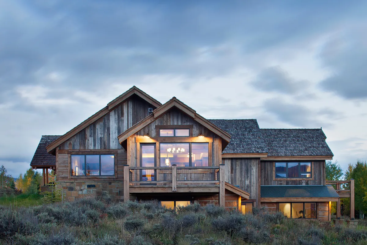 Rustic reclaimed wood home exterior in Crested Butte with soft evening lighting and custom gable rooflines.