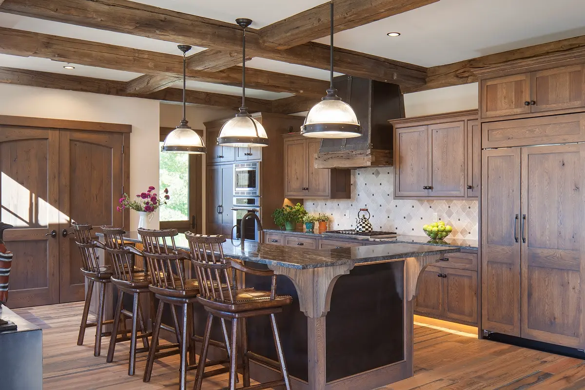 Rustic kitchen with wood cabinetry, black island, and pendant lighting in open-concept space.