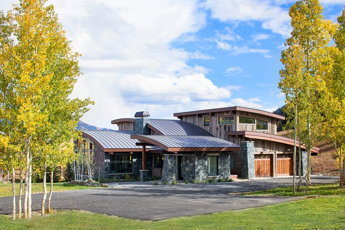 Exterior view of Surround House in Mount Crested Butte with curved roofs, glulam beams, and stone façade.