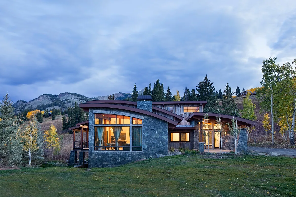Evening view of east-facing windows and organic stone-and-wood architecture at Surround House.