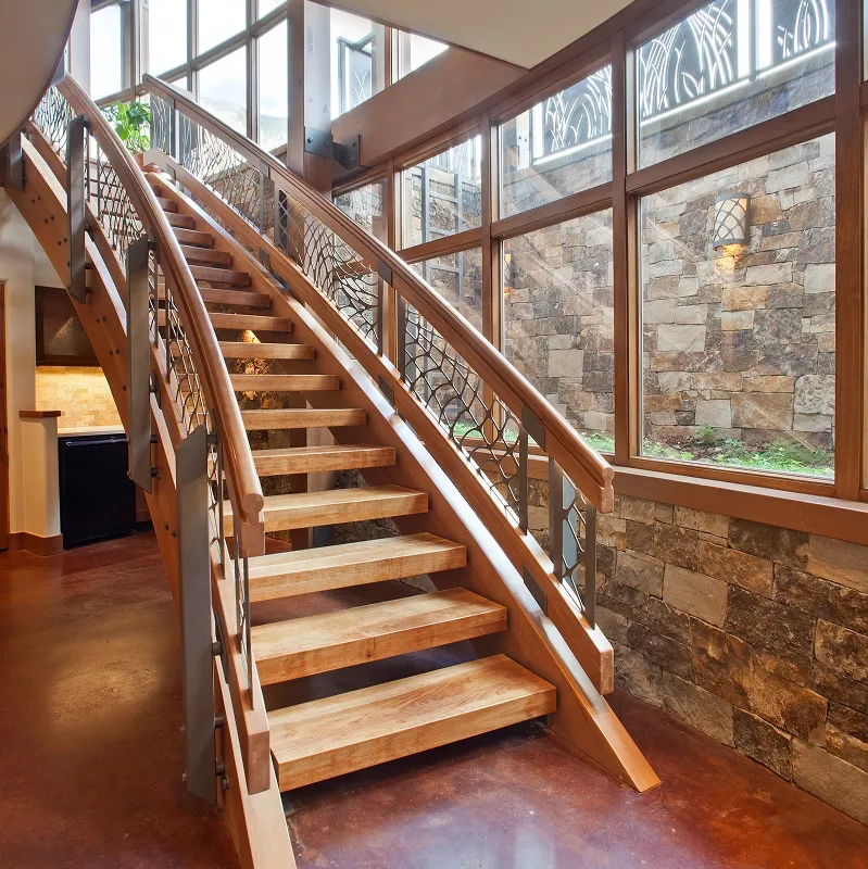 Lower level wood staircase with curved steel handrails and a stone retaining wall outside full-height windows.