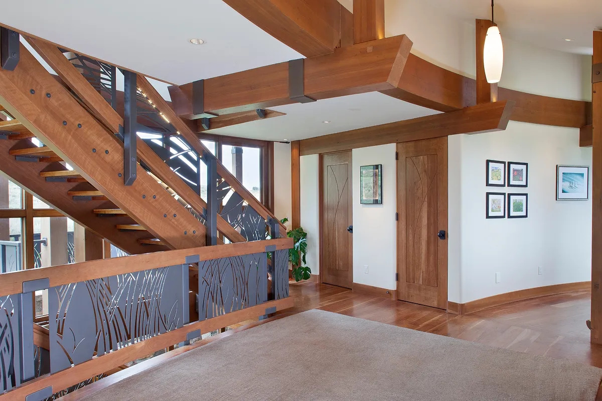 Upper stair landing with cherry wood details and custom metal railing in a modern mountain home.