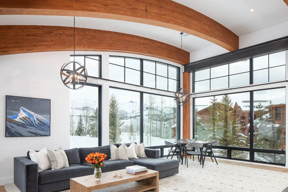 Contemporary mountain home living space with floor-to-ceiling windows, wood beams, and panoramic winter views in Crested Butte.